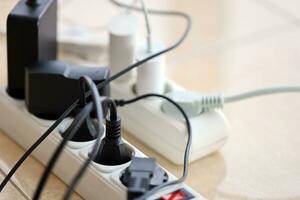 Overloaded power boards. Power strips with different electrical plugs on white floor photo