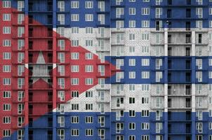 Cuba flag depicted in paint colors on multi-storey residental building under construction. Textured banner on brick wall background photo