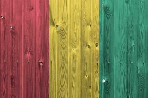 Guinea flag depicted in bright paint colors on old wooden wall. Textured banner on rough background photo