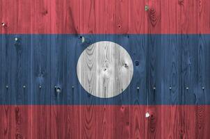 Laos bandera representado en brillante pintar colores en antiguo de madera pared. texturizado bandera en áspero antecedentes foto