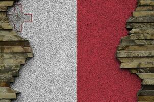 Malta flag depicted in paint colors on old stone wall closeup. Textured banner on rock wall background photo