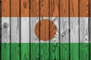 Niger flag depicted in bright paint colors on old wooden wall. Textured banner on rough background photo