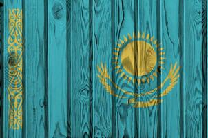 Kazakhstan flag depicted in bright paint colors on old wooden wall. Textured banner on rough background photo