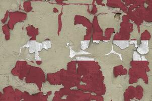 Latvia flag depicted in paint colors on old obsolete messy concrete wall closeup. Textured banner on rough background photo