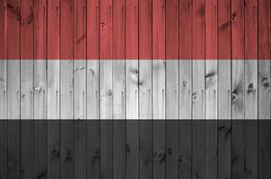 Yemen flag depicted in bright paint colors on old wooden wall. Textured banner on rough background photo