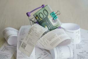 Euro bills bunch in shopping trolley surrounded by many paper receipts photo