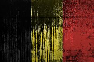 Belgium flag depicted in paint colors on old and dirty oil barrel wall closeup. Textured banner on rough background photo