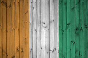Ivory Coast flag depicted in bright paint colors on old wooden wall. Textured banner on rough background photo