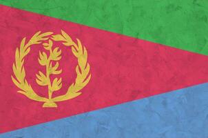 Eritrea flag depicted in bright paint colors on old relief plastering wall. Textured banner on rough background photo