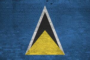 Saint Lucia flag depicted in paint colors on old brick wall. Textured banner on big brick wall masonry background photo