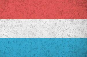 Luxembourg flag depicted in bright paint colors on old relief plastering wall. Textured banner on rough background photo