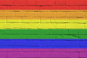 LGBT community flag depicted in paint colors on old brick wall. Textured banner on big brick wall masonry background photo