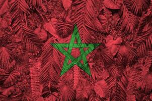 Morocco flag depicted on many leafs of monstera palm trees. Trendy fashionable backdrop photo