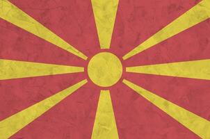 Macedonia flag depicted in bright paint colors on old relief plastering wall. Textured banner on rough background photo