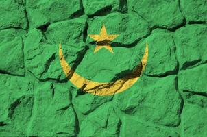 Mauritania flag depicted in paint colors on old stone wall closeup. Textured banner on rock wall background photo