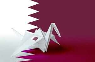 Qatar flag depicted on paper origami crane wing. Handmade arts concept photo