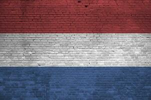 Netherlands flag depicted in paint colors on old brick wall. Textured banner on big brick wall masonry background photo