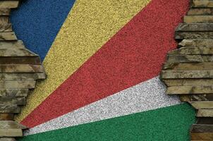 Seychelles flag depicted in paint colors on old stone wall closeup. Textured banner on rock wall background photo