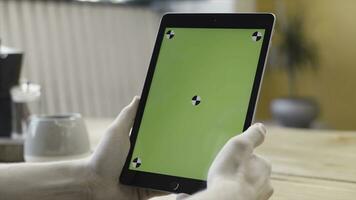 Close up of young man hands holding black tablet with green screen and tracking marks, technologies concept. Stock footage. Male hands using tablet with chroma key. photo