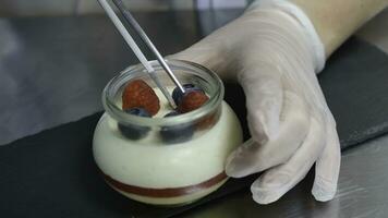 Homemade yogurt with blueberries in a glass jar. Hand putting Strawberry in Yogurt photo