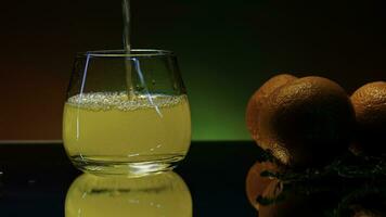 Close up of pouring orange soda into the glass. Stock clop. Soft drink with the taste of citrus and orange fruits on the reflective table surface. photo