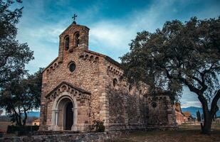 Catholic church located in Catalonia neighborhood. Red brick building surrounded by green tree foliage. photo