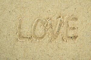 Love hand written text on sand photo