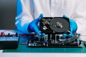Hard disk drive on the technician's desk and a computer motherboard as a component. the concept of data, hardware, and information technology. photo