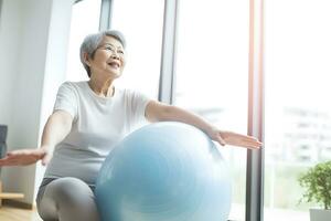 AI generated Senior Asian woman doing exercise with a swiss ball at a gym photo