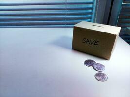 A box of savings and coins stacked on a table, for background purpose photo