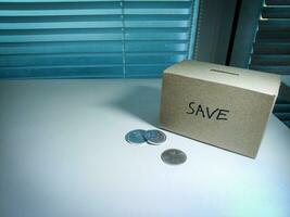 A box of savings and coins stacked on a table, for background purpose photo