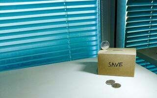 A box of savings and coins stacked on a table, for background purpose photo