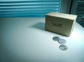 A box of savings and coins stacked on a table, for background purpose photo