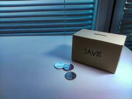 A box of savings and coins stacked on a table, for background purpose photo