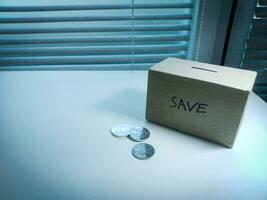 A box of savings and coins stacked on a table, for background purpose photo