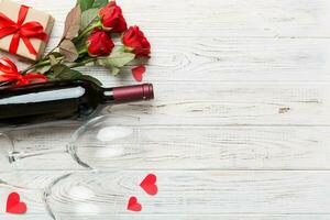 Valentine's day composition with red wine, rose flower and gift box on table. Top view, flat lay. Holiday concept photo