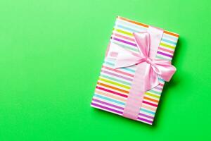 Top view Christmas present box with pink bow on green background with copy space photo