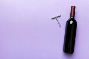 One Bottle of red wine with corkscrew on colored table. Flat lay, top view wth copy space photo