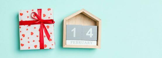 Top view of white gift boxes with hearts and wooden calendar on colorful background. The fourteenth of February. Valentine's Day concept photo