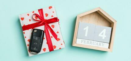 Top view of car key on a gift box with red hearts and festive calendar on colorful background. The fourteenth of february. Present for Valentine's Day concept photo