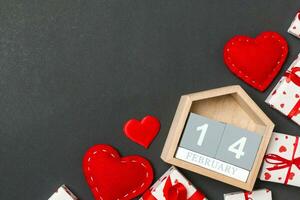 Top view of gift boxes, wooden calendar and red textile hearts on colorful background. The fourteenth of february. St Valentine's day concept with copy space photo