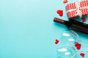 Valentine's day composition with red wine, rose flower and gift box on table. Top view, flat lay. Holiday concept photo