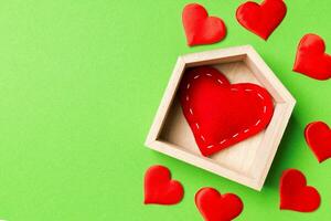 Top view composition made of red heart in a house surrounded with small hearts on colorful background. Home sweet home concept. Valentine's day photo