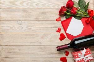Valentine's day composition with red wine, rose flower and gift box on table. Top view, flat lay, copy space photo