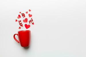 red cup on colored background, splashes of red little hearts, top view with copy space photo