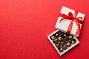 Delicious chocolate pralines in red box for Valentine's Day. Heart shaped box of chocolates top view with copy space photo