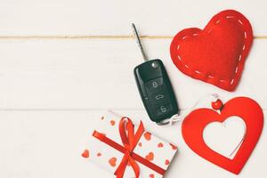 Top view of a present for Valentine's Day on wooden background. Car key, gift box and heart with copy space. Surprise concept for a holiday photo