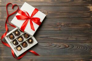 Delicious chocolate pralines in red box for Valentine's Day. Heart shaped box of chocolates top view with copy space photo