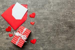 Red paper envelope with empty white card and heart on colored background. top view valentines day concept photo