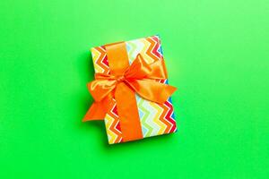 Top view Christmas present box with orange bow on green background with copy space photo